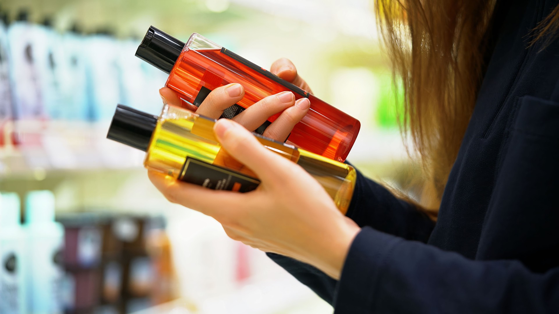 A female customer compares two shampoos reads the label examines the ingredients